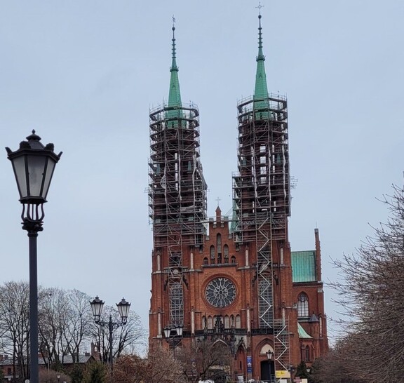 Widok na kościół od frontu. Dwie kościelne wieże są obudowane rusztowaniami.