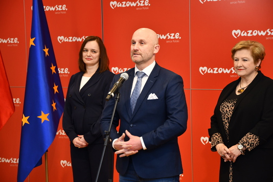 Mężczyzna elegancko ubrany przed mikrofonem.