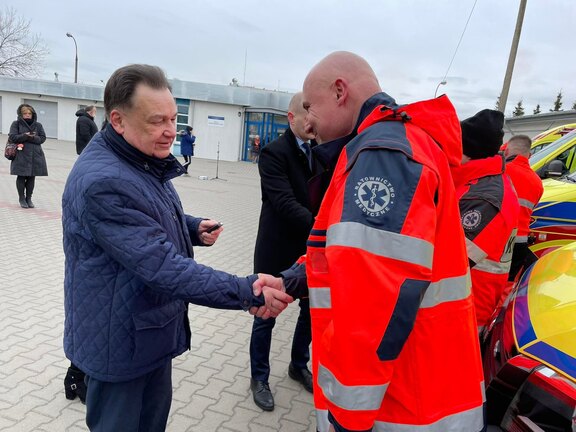 Marszałek Adam Struzik podaje rękę mężczyźnie ubranemu w strój ratownika medycznego