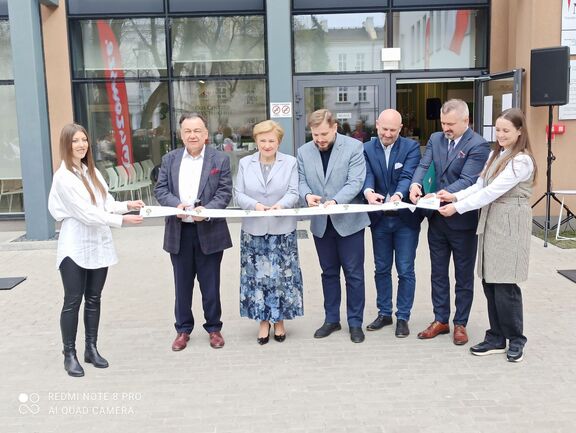 Otwarcie Centrum pomocy psychiatrycznej dla najmłodszych. Kilku uczestników wydarzenia przecina wstęgę przed budynkiem inicjując otwarcie placówki