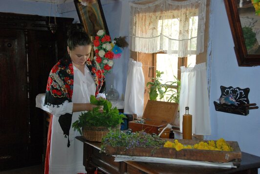 Widok na gospodynię w chacie pokazującą co jadło się na wsi na przednówku.