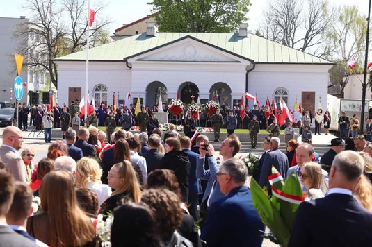 Zabytkowy budynek odwachu, przed którym stoją żołnierze i harcerze z flagami