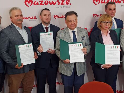 Marszałek stoi między kobietą a dwoma mężczyznami. Wszyscy prezentują podpisane listy intencyjne