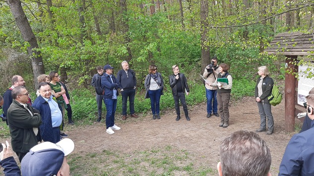 Uczestnicy spotkania stoją na leśnej polance