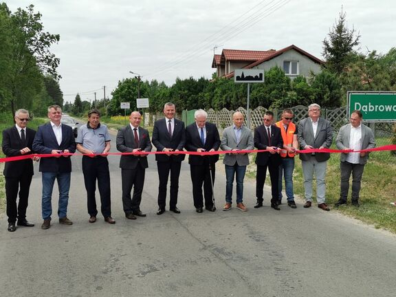 Mężczyźni przecinają wstęgę na otwarciu nowego odcinka drogi.