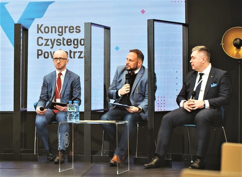 Trzech mężczyzn prowadzących dyskusję, w tle plansza V Kongres Czystego Powietrza