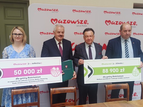 Trzech mężczyzn i jedna kobieta pozują do zdjęcia z czekiem