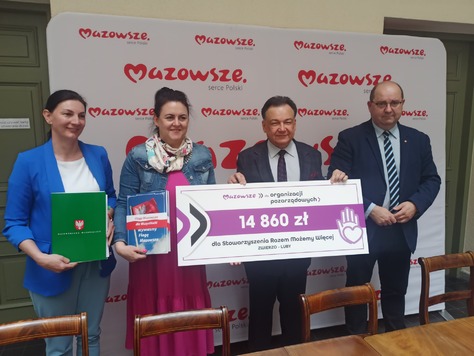 Dwóch mężczyzn i dwie kobiety pozują do zdjęcia z czekiem