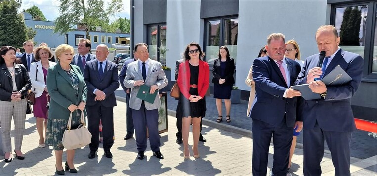 Marszałek Struzik oraz członkinie zarządu stoją obok siebie na placu i słuchają przemówień. Za nimi widać innych uczestników spotkania