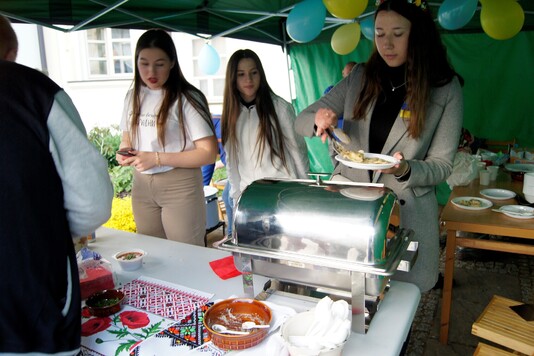 Degustacja potraw ukraińskich. Widok na trzy panie obsługujące stoisko.