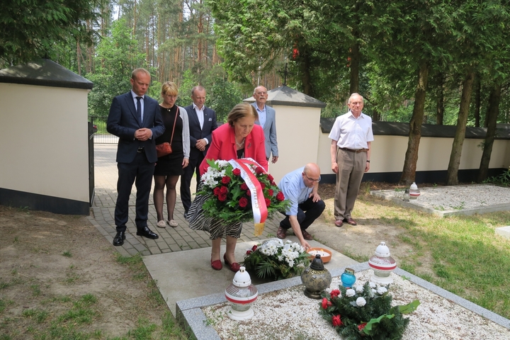 Przewodnicząca Komisji Kultury i Dziedzictwa Narodowego Jadwiga Zakrzewska składa wieniec przed zbiorowym grobem poległych w walkach w Ossowie. Wiceburmistrzem gminy Wołomin Dariuszem Szymanowski stawia zapalony znicz. W tle pozostali członkowie komisji.