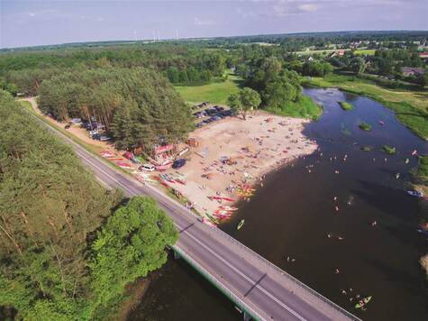 Widok z lotu ptaka na plażę przy zbiorniku wodnym oraz most.