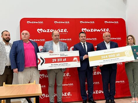 Na zdjęciu grupa mężczyzn pozuje do zdjęcia z czekami