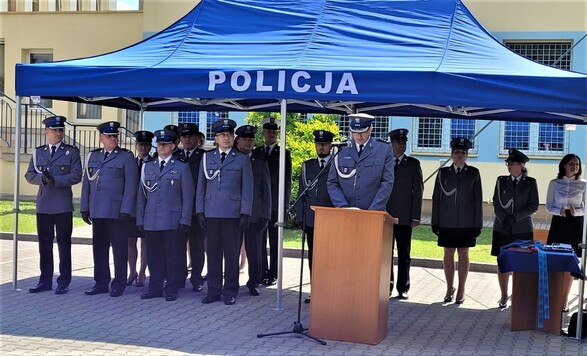 Komendant policji stoi przy ambonie. Za nim, pod namiotem stoją w szeregu pozostali funkcjonariusze