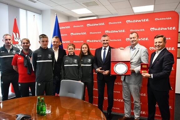 Wicemarszałkowie pozują do zdjęcia z przedstawicielami dwóch drużyn. Wicemarszałek Raboszuk prezentuje kamerze jeden ze zdobytych trofeum - medal w formie dyplomu