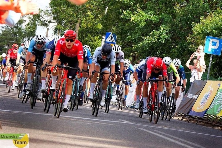 Jadący peleton kolarzy. Na przedzie widać dwóch kolarzy w koszulkach Mazowsza