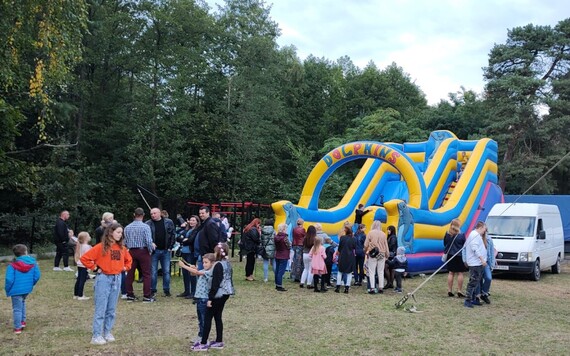 Przed dmuchaną zjeżdżalnią stoją uczestnicy imprezy, głównie dzieci