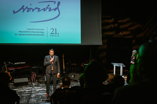 Na scenie Sali kameralnej Teatru Polskiego przy mikrofonie stoi wiceprzewodniczący Sejmiku Województwa Mazowieckiego Marcin Podsędek.