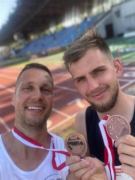 dwóch mężczyzn w stroju sportowym pozuje do zdjęcia na stadionie.