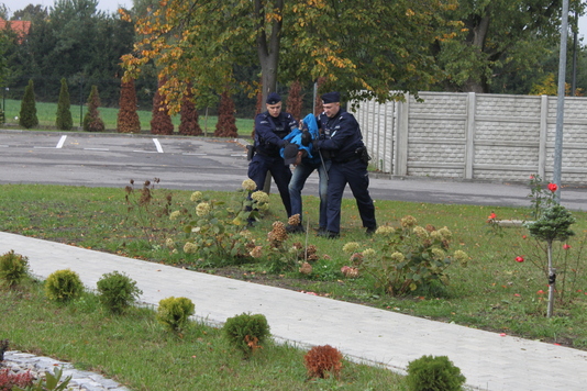 Dwaj policjanci prowadzą obezwładnionego młodego mężczyznę