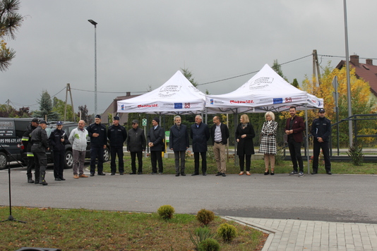 Grupa ludzi stoi w rzędzie na placu