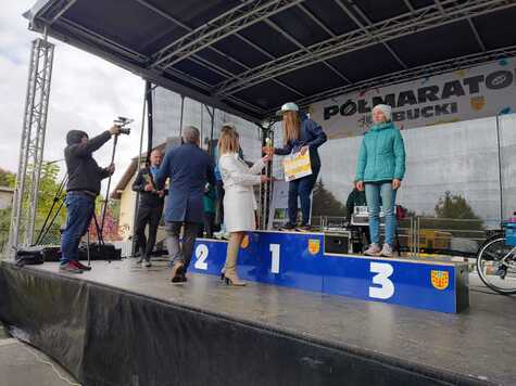 Członek zarządu Orzełowska podaje puchar stojącej na podium zawodniczce