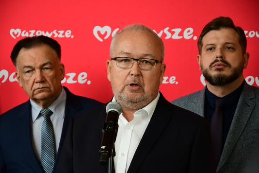 Mężczyzna w garniturze stoi przed mikrofonem