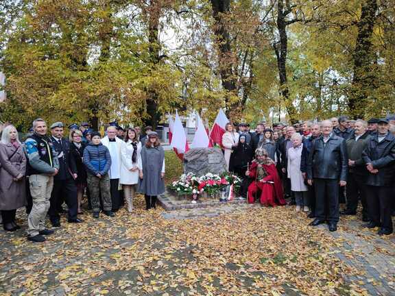 Tablica pamiątkowa a wokół niej osoby biorące udział w wydarzeniu