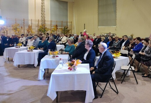 Przy każdym stoliku ustawionym na sali siedzi para seniorów