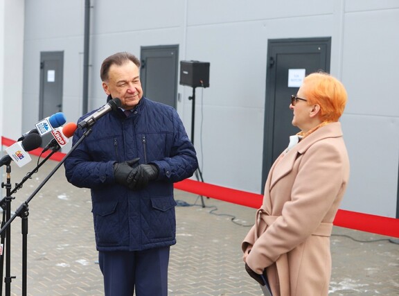 Marszałek stoi na zewnątrz przed mikrofonami i patrzy się na kobietę, która stoi obok niego.