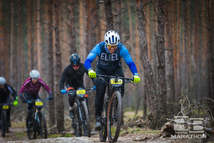 Rowerzysta na rowerze górskim jedzie pod górę leśną ścieżką