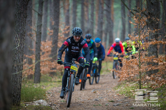 Peleton kolarzy jedzie leśną ścieżką