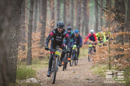 Kolarze na rowerach jadący leśną ścieżką