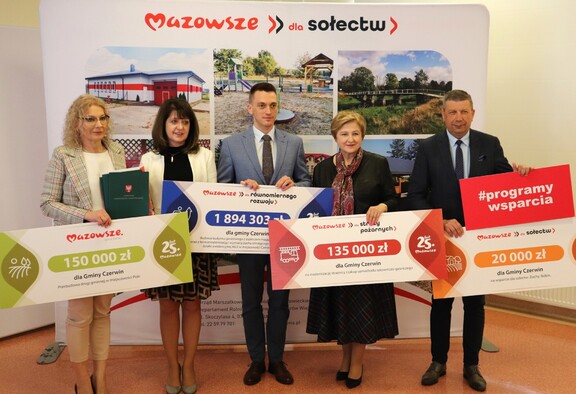 Przedstawiciele władz z tablicami informacyjnymi zawierającymi kwoty dofinansowania.