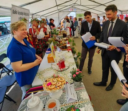 Stół z produktami spożywczymi i uczestnicy wydarzenia.