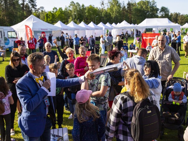 Prowadzący piknik podaje uczestnikom grę Monopoly Mazowsze