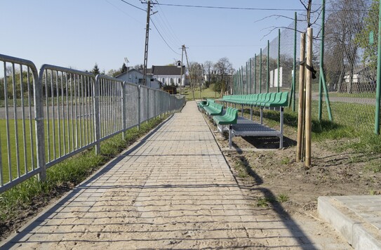 Chodnik z kostki brukowej przy boisku.