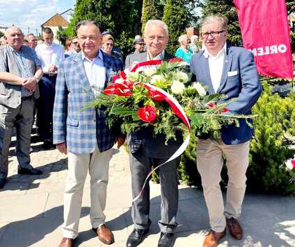 Trzech mężczyzn niesie wieniec.