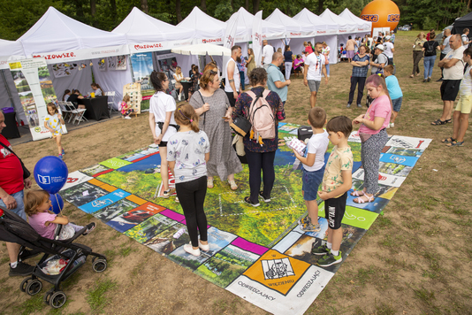 Uczestnicy pikniku grają w plenerową wersję gry planszowej Mazopolis