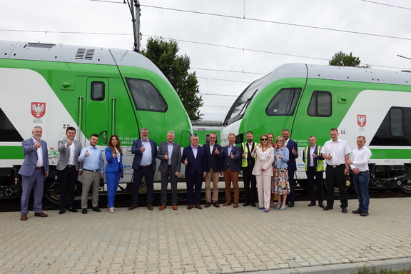 Nowe pociągi przed nimi stoją uczestnicy konferencji