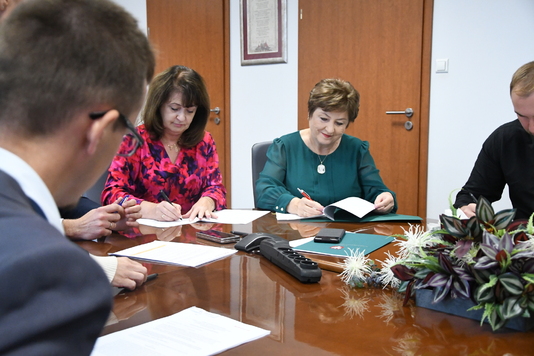 Członkinie zarządu Elżbieta Lanc i Janina Ewa Orzełowska podpisują umowy przy stole