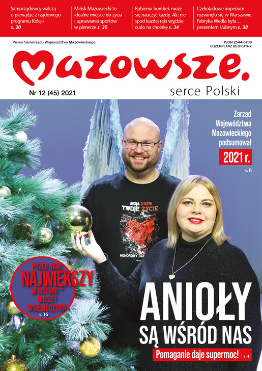 para wolontariuszy pozuje do zdjęcia przy choince