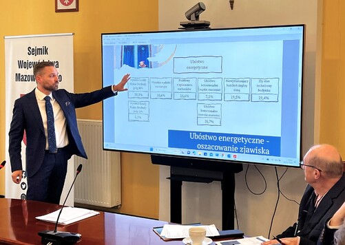 Profesor omawia wyniki badania stojąc przed ekranem telewizora