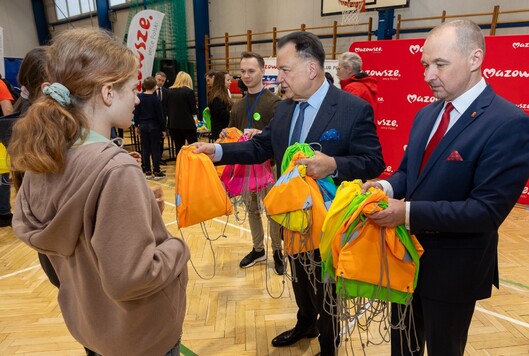 Marszałek Adam Struzik wręcza uczennicy plecak odblaskowy