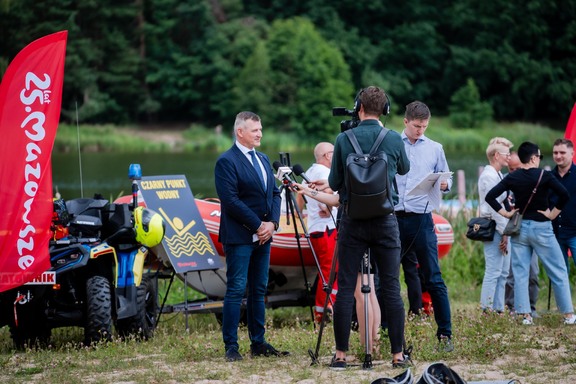 Wicemarszałek Rafał Rajkowski udziela wywiadu przy oznaczonym czarnym punkcie wodnym