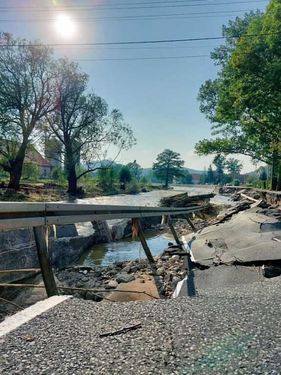 zniszczony asfalt, wyłamane barierki energochłonne i zepsute nabrzeże rzeki