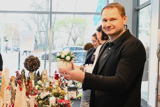 Jeden z uczestników kiermaszu trzymający stroik świąteczny.