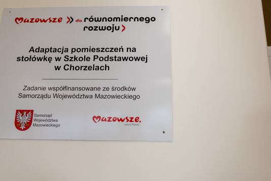 Przedstawiciele szkoły podczas otwarcia nowej stołówki słuchają przemawiającego na sali