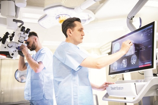 Dwóch lekarzy w szpitalnej sali diagnostycznej, stojących przy aparaturze medycznej.