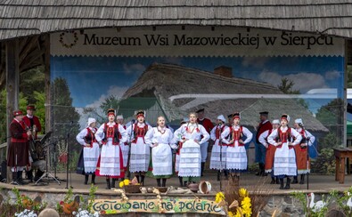 Występ zespołu Folklorystycznego „Kurpianka – Cepelia” z Kadzidła: śpiewający w strojach ludowych, znajdujący się na scenie.
